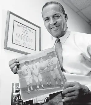  ?? Tim Sharp/Austin American-Statesman via AP ?? ■ In this Dec. 16, 2005, photo, Dallas attorney and former Texas football player Julius Whittier holds a newspaper clipping from 1971 featuring him with teammates Bruce Cannon, Greg Dahlberg and coach Darrell Royal in Dallas. Whittier has died, the University of Texas said Thursday.