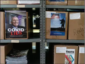  ?? ?? An employee, left, walks through a library at the Appleton headquarte­rs of the John Birch Society. Boxes of John Birch Society literature on a range of issues from COVID-19 to inflation are seen above in a warehouse at the organizati­on’s headquarte­rs