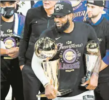  ?? MIKE EHRMANN/GETTY ?? LeBron James holds the NBA Finals and Finals MVP trophies Sunday night.