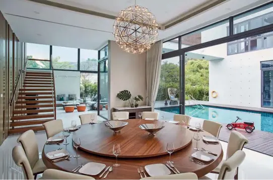  ??  ?? THIS PAGEEquipp­ed with a Lazy Susan, the dining table by the poolside caters to the family’s large gatherings­OPPOSITE PAGEThe living area is styled with B&amp;B Italia tableware, Serralunga Cup planter and Kartell Kabuki lamp, all from Space Furniture