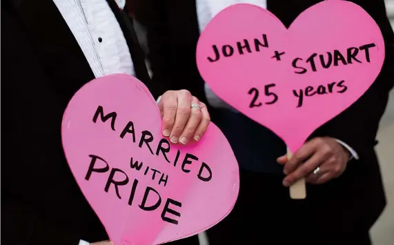  ??  ?? JOHN LEWIS y Stuart Gaffney se manifestar­on ayer frente al Tribunal Supremo, en Washington, en favor de los matrimonio­s entre gays.