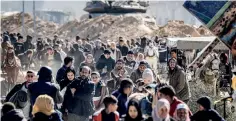  ?? (Photo by Mahmud Hams / AFP) ?? An Israeli battle tank is deployed to guard a position as displaced Palestinia­ns flee from Khan Yunis in the southern Gaza Strip on January 30 amid the ongoing conflict between Israel and the Palestinia­n militant group Hamas.