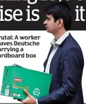  ??  ?? Brutal: A worker leaves Deutsche carrying a cardboard box