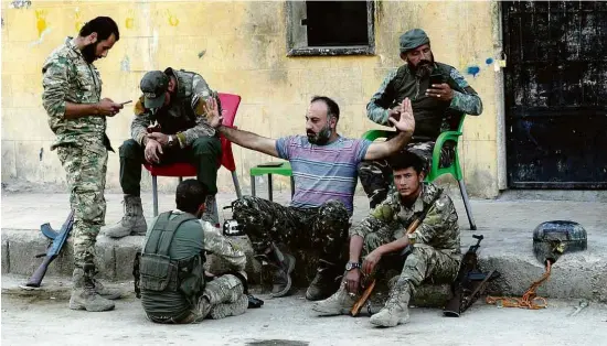  ?? Khalil Ashawi/Reuters ?? Combatente­s rebeldes sírios apoiados pela Turquia descansam juntos em Tal Abyad, na Síria, onde havia postos com militares americanos