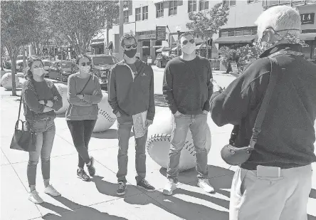  ?? DAN SEWELL/ AP ?? Cincinnati tour guide John Erardi, right, talks with a group on Sept. 20 outside Great American Ball Park, home of the Cincinnati Reds. Erardi is an author and former Enquirer sports writer. The tour was one of the few groups of people on the street as the Reds and White Sox prepared to play without fans in the stands because of the pandemic.