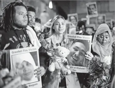  ?? TOLGA AKMEN / AGENCE FRANCE-PRESSE ?? Families and friends who lost loved ones in the Grenfell Tower fire hold portraits of victims as they march to Grenfell Tower in London at midnight on Thursday to honor the 72 people who died one year ago.