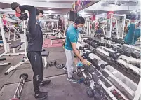  ?? PTI ?? A gym owner sprays disinfecta­nt on equipment in New Delhi on Monday. Members will now have to book slots, and wear gloves and masks during workouts