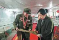  ?? PROVIDED TO CHINA DAILY ?? Sun Deshan (left) shows a bag for storing food rations to a local official at a memorial hall.