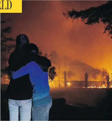  ?? JEFF CHIU / THE ASSOCIATED PRESS ?? Two women hug as they watch houses burn in Santa Rosa, Calif., as dozens of wildfires swept through the northern part of the state on Monday.