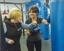  ??  ?? Below: Laurie Mushinsky, left, co-owner of Fit 4 Boxing Club in Hampton, instructs 69-year-old Linda Kozik.
