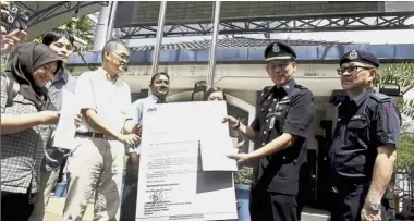  ??  ?? Official request: Ngeow (partially hidden) handing over the memorandum to DSP Faizal (second from right) at Bukit Aman in Kuala Lumpur.