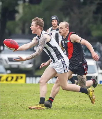  ?? ?? Poowong’s Jarvis Brown fires off a handball before Nilma-Darnum’s Ethan Carlisle closes in.