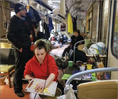  ?? THOMAS PETER / REUTERS ?? A woman prepares food in an unused subway car that has been converted to living quarters at a subway station that serves as a bomb shelter in Kharkiv, Ukraine, on March 27. Many Kharkiv families have spent four weeks undergroun­d.