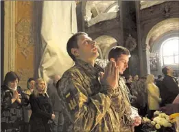  ?? Carolyn Cole Los Angeles Times ?? SOLDIERS and civilians pray inside Sts. Peter and Paul Garrison Church on Sunday in Lviv, Ukraine. The church is enmeshed with military families’ lives.