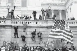  ?? JOSE LUIS MAGANA AP Photo ?? Rioters scale a wall at the U.S. Capitol on Jan. 6, 2021, in Washington.