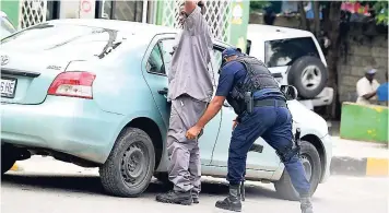  ??  ?? A policeman conducts a search in Flankers, St James.