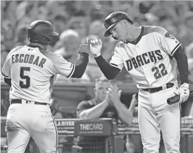  ?? JOE CAMPOREALE/USA TODAY SPORTS ?? The Diamondbac­ks’ Eduardo Escobar celebrates with Jake Lamb after scoring a run against the Colorado Rockies during Sunday’s game at Chase Field. The Diamondbac­ks swept the three-game series.