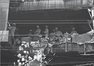  ?? SAJJAD HUSSAIN / AFP ?? National Disaster Response Force personnel in New Delhi on Saturday clear debris from a burned floor of a commercial building a day after a fire broke out.