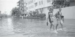  ?? JOE RAEDLE/GETTY ?? People walk through a flooded Miami Beach street that was caused by the combinatio­n of the lunar orbit, which caused seasonal high tides and what many believe is rising sea levels due to climate change.