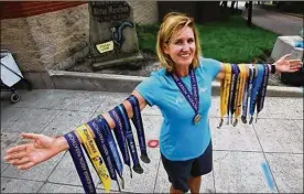  ?? MIKE CARDEW / THE BEACON JOURNAL ?? Melissa Johnson, 50, of Canton, a stepmother and grandmothe­r, shows off the medals she has earned from running in every Akron marathon since the first one in 2003. Today, she’ll run again in Akron for her 100th marathon.