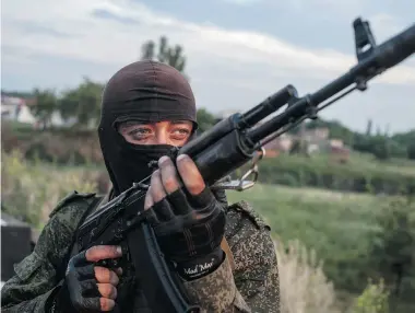  ?? EVGENIY MALOLETKA/The Associated Press ?? A pro-Russian fighter holds a gun during a handover Thursday of the bodies of Ukrainian troops killed in a plane shot down near Luhansk. Russia is resuming its military buildup along the Ukrainian border in an attempt to intimidate its neighbour.