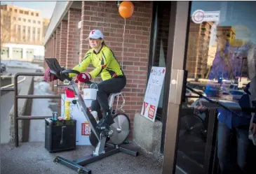  ?? Herald photo by Tijana Martin ?? Pam Haapa-Aho, a fitness manager with the YMCA, uses the exercise bike outside the YMCA entrance to greet visitors while promoting the “Build Strong Kids” fundraisin­g event on Monday. @TMartinHer­ald