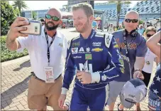  ?? John Raoux / The Associated Press ?? A race fan takes a photo with Dale Earnhardt Jr. as others try to get autographs after Friday’s NASCAR cup practice session.