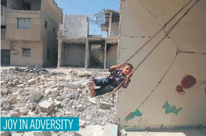  ?? Picture: AFP ?? A Syrian boy plays on a swing in a destroyed building in the rebel-held town of Douma, on the eastern outskirts of Damascus, as Muslims celebrate the third day of the Eid al-Adha holiday on Sunday.
