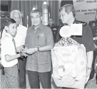  ??  ?? AHMAD Bashah (dua, kanan) menyampaik­an sumbangan kepada Shahrul Izwan Shahrim,14, pada Program Ihya Ramadan kepada balu, anak yatim dan anak istimewa warga polis di Dewan Utama Ibu Pejabat Polis Kontinjen (IPK) Kedah kelmarin. - Gambar BERNAMA