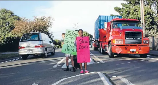  ??  ?? Dangerous: School children display homemade signs to slow traffic near the so-called crossing on State Highway 1 in Otaki.