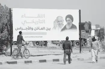  ?? ANMAR KHALIL/AP ?? Iraqis pass a poster announcing the upcoming visit of Pope Francis in Najaf. The pope is scheduled to meet the Grand Ayatollah Ali al-Sistani, right, on Saturday at the cleric’s home. Al-Sistani rarely receives foreign dignitarie­s.
