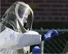  ?? ANGELA ROWLINGS / HERALD STAFF FILE ?? VIRUS TAKES TOLL: Registered nurse Trish Lapolla prepares to test a patient for COVID-19 outside Cambridge Health Alliance’s Somerville Hospital on March 18.