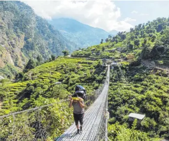  ?? FOTO: DPA ?? Das schwere Gepäck der Trekkinggr­uppen schleppen nepalesisc­he Träger durch die Terrassenf­elder.