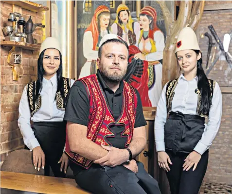  ?? ?? Home from home: Olti Bokciu, co-owner of the Illyrian Grill House, an Albanian restaurant in Palmers Green, with two of his employees. The 33-year-old also has a building firm