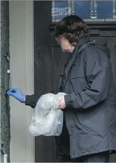  ?? RICHARD LAM ?? A police investigat­or cleans the front entryway of a house on Crescent Road in south Surrey, following an early morning shooting in which a man was killed and a woman seriously injured.