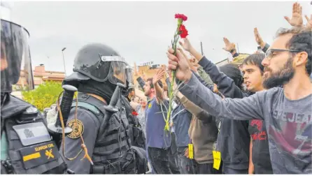  ?? Foto: Getty Images ?? Demonstran­ten in dem katalanisc­hen Ort Sant Julia de Ramis halten den Polizisten Blumen entgegen.