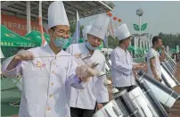  ?? AP ?? Chefs prepare to cook buns in a solar cooker that using a metal and glass vacuum tube heated by mirrors curved to capture the sun’s heat in Dezhou in the eastern Shandong province in China. —