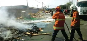  ?? AGAS PUTRA HARTANTO/JAWA POS ?? JINAKKAN API: Petugas PMK menyemprot­kan air ke tumpukan kayu palet yang terbakar di Jalan Pintu Air, Krembangan, kemarin (10/9).