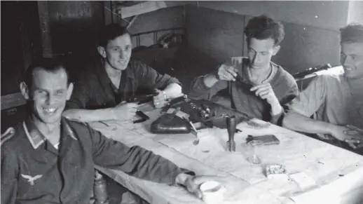  ??  ?? Alexander Wolff’s father, Nikolaus (second from right), cleaning his pistol, with his German army unit during World War II