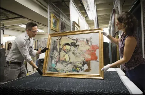  ??  ?? In this Aug. 9 photo provided by the University of Arizona, Willem de Kooning's "Woman-Ochre" is readied for examinatio­n by Nathan Saxton, right, an exhibition­s specialist, and Kristen Schmidt, a registrar, in Phoenix. AP PHOTO