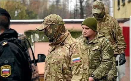  ?? AP ?? A Ukrainian sailor, second right, is escorted by Russian intelligen­ce agency FSB officers from a court in Simferopol, Crimea.