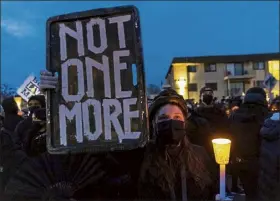  ?? KEREM YUCEL / getty images ?? Demonstrat­ors hold candles and signs as they protest peacefully ahead of the 10 p.m. curfew thursday in front of the Brooklyn Central police station in Brooklyn Center, minn.