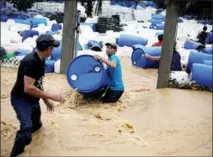  ?? JORGE CABRERA / REUTERS ?? Men recover plastic barrels from a business affected by flooding caused by rains from Hurricane Eta in Toyos, Honduras, on Nov 4. Eta has left at least one person dead and more than 450 people homeless after lashing Honduras with strong winds and rain, local authoritie­s said on Nov 4.