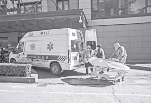  ?? QILAI SHEN/BLOOMBERG ?? HEALTH workers in protective gear transport a bed outside the emergency room of a hospital in Shanghai last year. China’s health care system has been inundated by Covid patients, and questions are arising over the real impact of the latest wave.