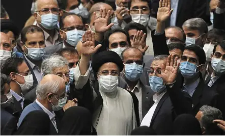  ??  ?? New era: Raisi (centre, in white) waving to journalist­s as he is surrounded by lawmakers after taking his oath as president at Iran’s Parliament in tehran. — ap