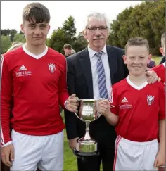  ??  ?? Ian Lawlor presenting the trophy to Moyne Rangers joint captains Kian Murphy and Dylan Browne.