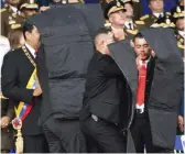  ?? — AP ?? Security personnel surround Venezuela’s President Nicolas Maduro ( left) during an incident as he was giving a speech in Caracas on Saturday. Drones armed with explosives detonated near Mr Maduro as he gave a speech to hundreds of soldiers in Caracas on Saturday, but the socialist leader was unharmed.