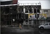  ?? MASOUME ALIAKBAR — ISNA ?? People walk past buildings which burned during protests that followed the authoritie­s’ decision to raise gasoline prices in the city of Karaj, west of the capital Tehran, Iran.