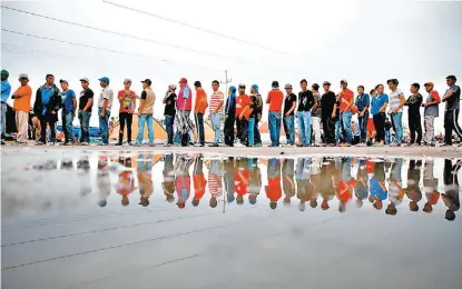  ?? REUTERS ?? Migrantes forman una fila para recibir comida en la Unidad Deportiva Benito Juárez.