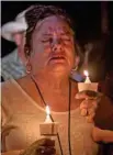  ??  ?? A mourner attends a candle light vigil after a mass shooting.